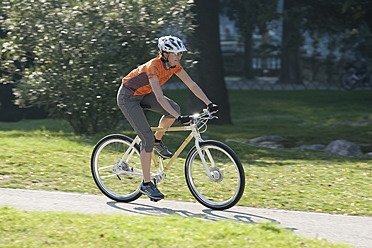 Italien, Riva del Garda, Mittlere erwachsene Frau fährt Fahrrad - DSF000447