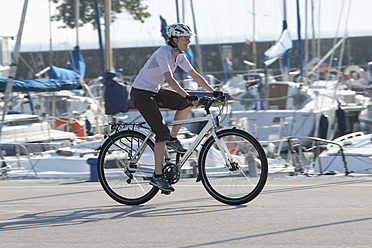 Italien, Riva del Garda, Mittlere erwachsene Frau fährt Fahrrad - DSF000446