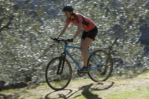 Italy, Mid adult woman riding bicycle stock photo