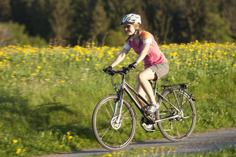 Deutschland, Bayern, Junge Frau fährt Fahrrad, lizenzfreies Stockfoto