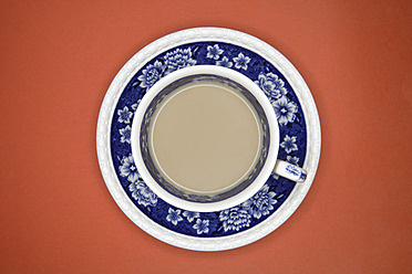 Cup of coffee with saucer on orange background, close up - TCF002318