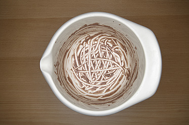 Ausgeleckte Schale mit Schokoladenpudding auf Holztisch, Nahaufnahme - TCF002342