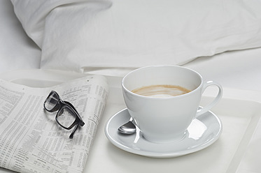 Tablett mit Kaffee, Zeitung und Brille auf dem Bett, Nahaufnahme - CRF002176