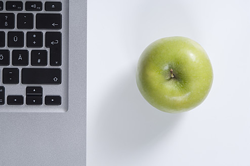 Laptop und grüner Apfel auf weißem Hintergrund - ASF004525