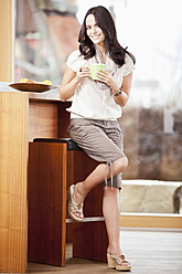 Germany, Bavaria, Young woman with cup, smiling, portrait - MAEF004551