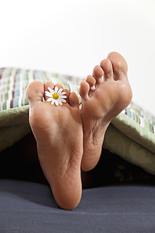 Deutschland, Bayern, Menschlicher Fuß mit Blume auf Bett - MAEF004604