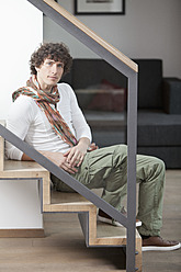 Germany, Bavaria, Young man sitting on steps at home, portrait - MAEF004634