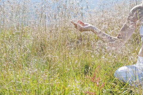 Austria, Salzburg County, Young woman sitting in alpine meadow and doing meditation stock photo