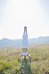 Austria, Salzburg County,, Young woman doing headstand in alpine meadow - HHF004064