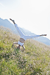 Austria, Salzburg County,, Young woman doing headstand in alpine meadow - HHF004065