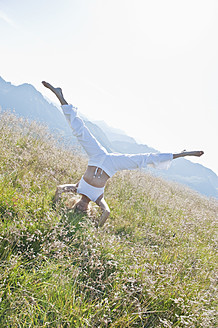 Austria, Salzburg County,, Young woman doing headstand in alpine meadow - HHF004065