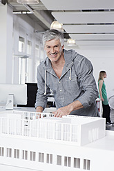 Deutschland, Bayern, München, Mann stehend mit Architekturmodell im Büro - RBYF000017