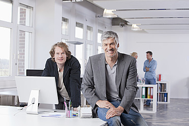 Germany, Bavaria, Munich, Men sitting at computer table in office - RBYF000101