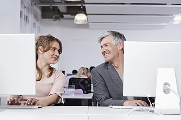 Germany, Bavaria, Munich, Man and woman using computer in office, smiling - RBYF000070