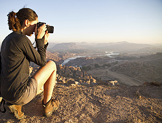 Indien, Karnataka, Junge Touristin beim Fotografieren auf einem Hügel in Hampi - MBEF000323