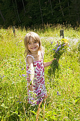 Österreich, Land Salzburg, Mädchen pflückt Blumen auf Sommerwiese, lächelnd, Porträt - HHF004076