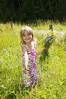 Austria, Salzburg County, Girl picking flowers in summer meadow, smiling, portrait - HHF004076