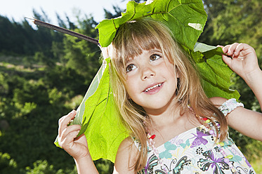 Austria, Salzburg, Girl carrying leaf on head, smiling - HHF004077