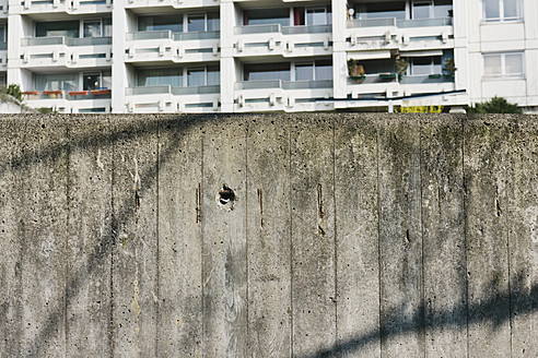 Germany, Bavaria, Munich Westend, Concrete wall in front of high rise - LFF000416