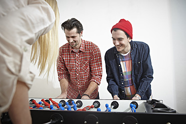 Germany, Cologne, Men and woman playing table soccer, smiling - RHYF000006