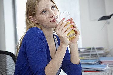 Germany, Cologne, Young woman with juice in apartment - RHYF000048