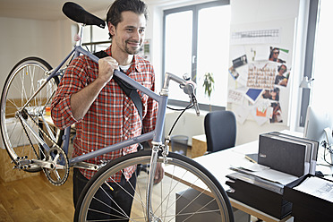 Deutschland, Köln, Mittlerer erwachsener Mann mit Fahrrad, lächelnd - RHYF000061