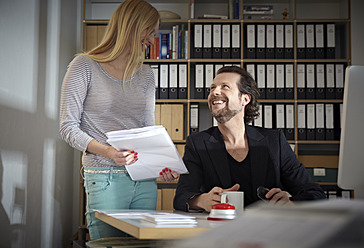 Deutschland, Köln, Mann und Frau arbeiten im Büro, lächelnd - RHYF000079