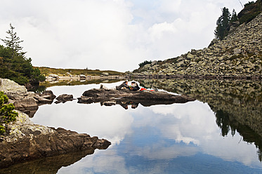 Österreich, Steiermark, Mann und Frau liegen auf einem Felsen am Spiegelsee - HHF004085