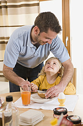 Father spreading butter on bread for daughter breakfast - RNF000849