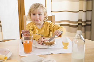 Girl spreading jam on bread, smiling - RNF000853