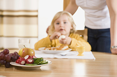 Frisches Obst auf dem Tisch, Mädchen beim Frühstück im Hintergrund - RNF000856