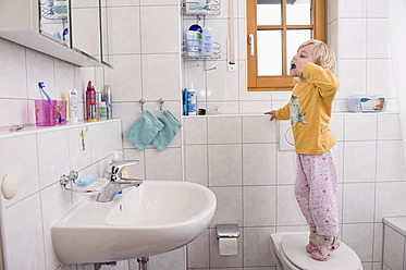 Girl standing on toilet, brushing teeth in bathroom - RNF000866