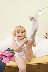 Mädchen zieht sich auf dem Bett an, zieht Socken an - RNF000891