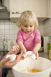 Girls pouring egg yolk in mixing bowl - RNF000901