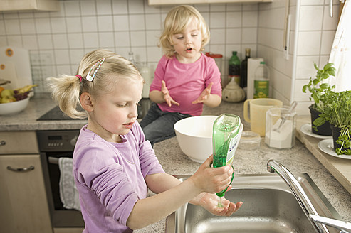 Mädchen wäscht Hände, Schwester sitzt im Hintergrund - RNF000902