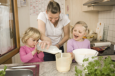 Mother and daughter pouring milk into measuring cup - RNF000916