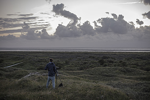 Niederlande, Mann stehend mit Kamera an der Nordsee - DWF000169