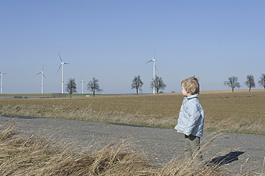 Deutschland, Sachsen, Junge steht auf der Straße, Windrad im Hintergrund - MJF000016