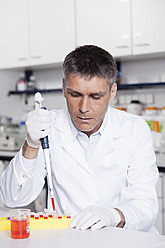 Deutschland, Bayern, München, Wissenschaftlerin gießt rote Flüssigkeit mit Pipette in Reagenzglas für medizinische Forschung im Labor - RBF000821