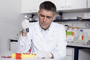 Deutschland, Bayern, München, Wissenschaftlerin gießt rote Flüssigkeit mit Pipette in Reagenzglas für medizinische Forschung im Labor - RBF000822