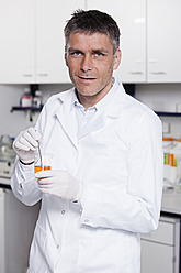 Germany, Bavaria, Munich, Scientist with liquid in beaker for medical research in laboratory - RBF000824