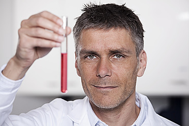 Deutschland, Bayern, München, Wissenschaftlerin hält rote Flüssigkeit in Reagenzglas für medizinische Forschung im Labor - RBF000830