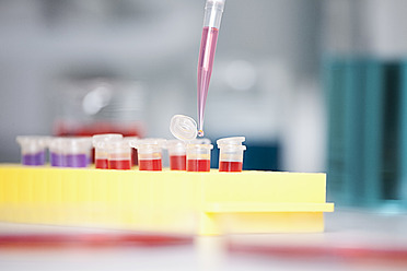 Germany, Bavaria, Munich, Pipette pouring liquid into test tubes for medical research - RBF000841