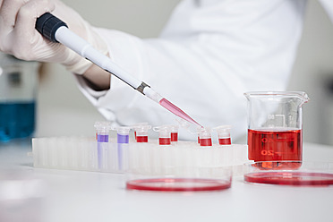 Deutschland, Bayern, München, Wissenschaftler gießt rote Flüssigkeit in Reagenzglas für medizinische Forschung im Labor - RBF000848