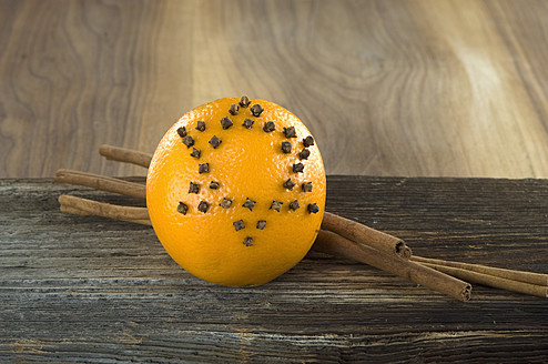 Orange studded with cloves and cinnamon stick on table, close up - ASF004545