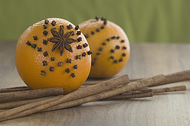Orange gespickt mit Nelken und Sternanis, Zimtstange auf dem Tisch - ASF004549