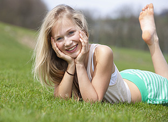 Austria, Teenage girl lying on meadow, smiling, portrait - WWF002317