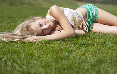 Austria, Teenage girl lying on meadow, smiling, portrait - WWF002318