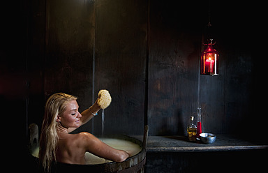 Austria, Salzburg County, Young woman taking bath in wooden tub - HHF004175
