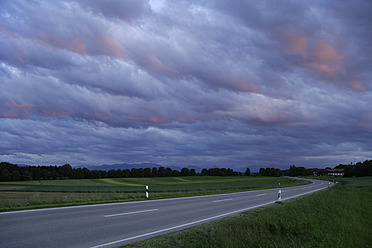 Deutschland, Bayern, Blick auf leere Straße zu Alpen mit bewölktem Himmel - TCF002500